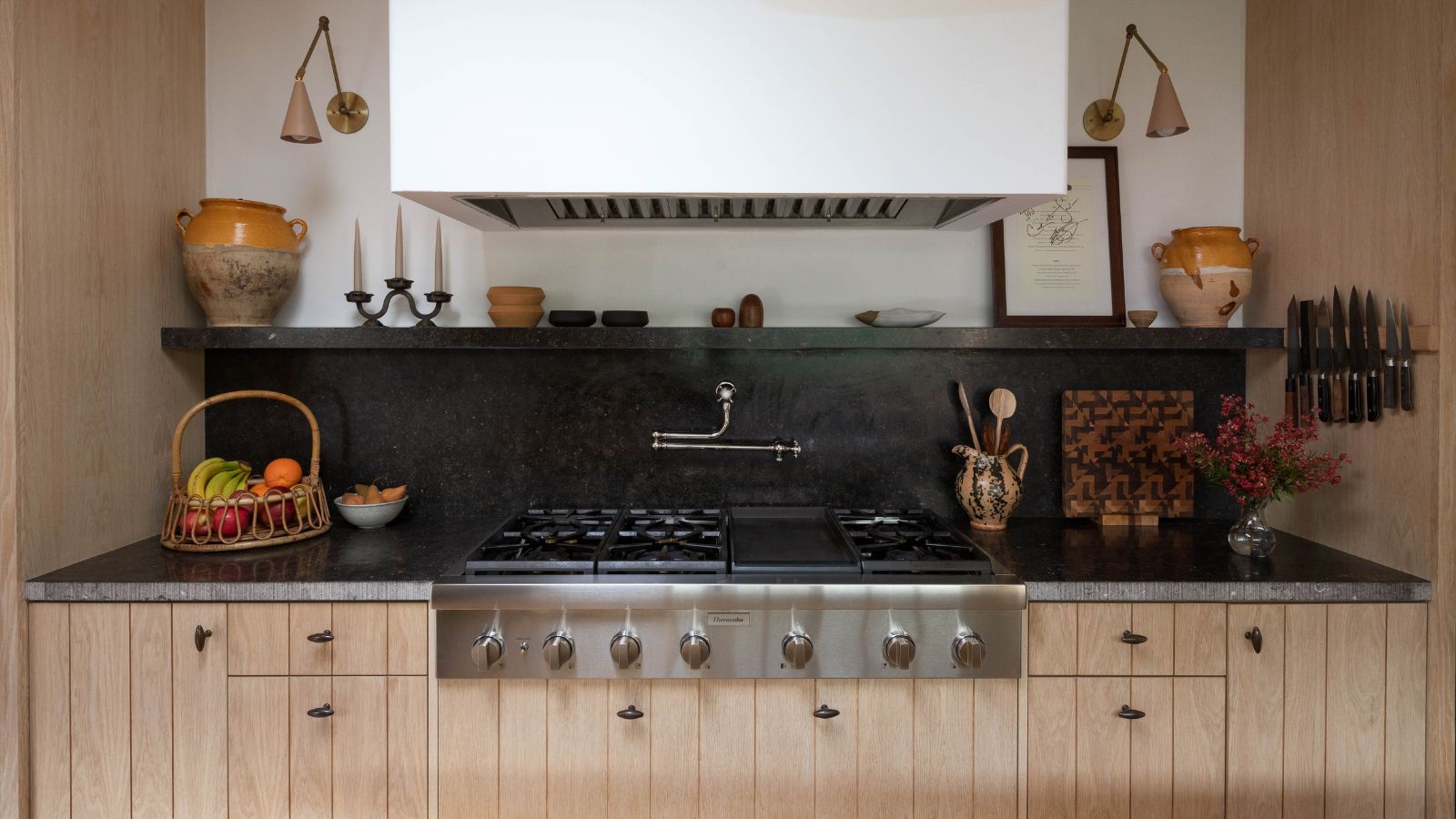 A kitchen with white walls, paneled wooden cabinetry, and granite countertops