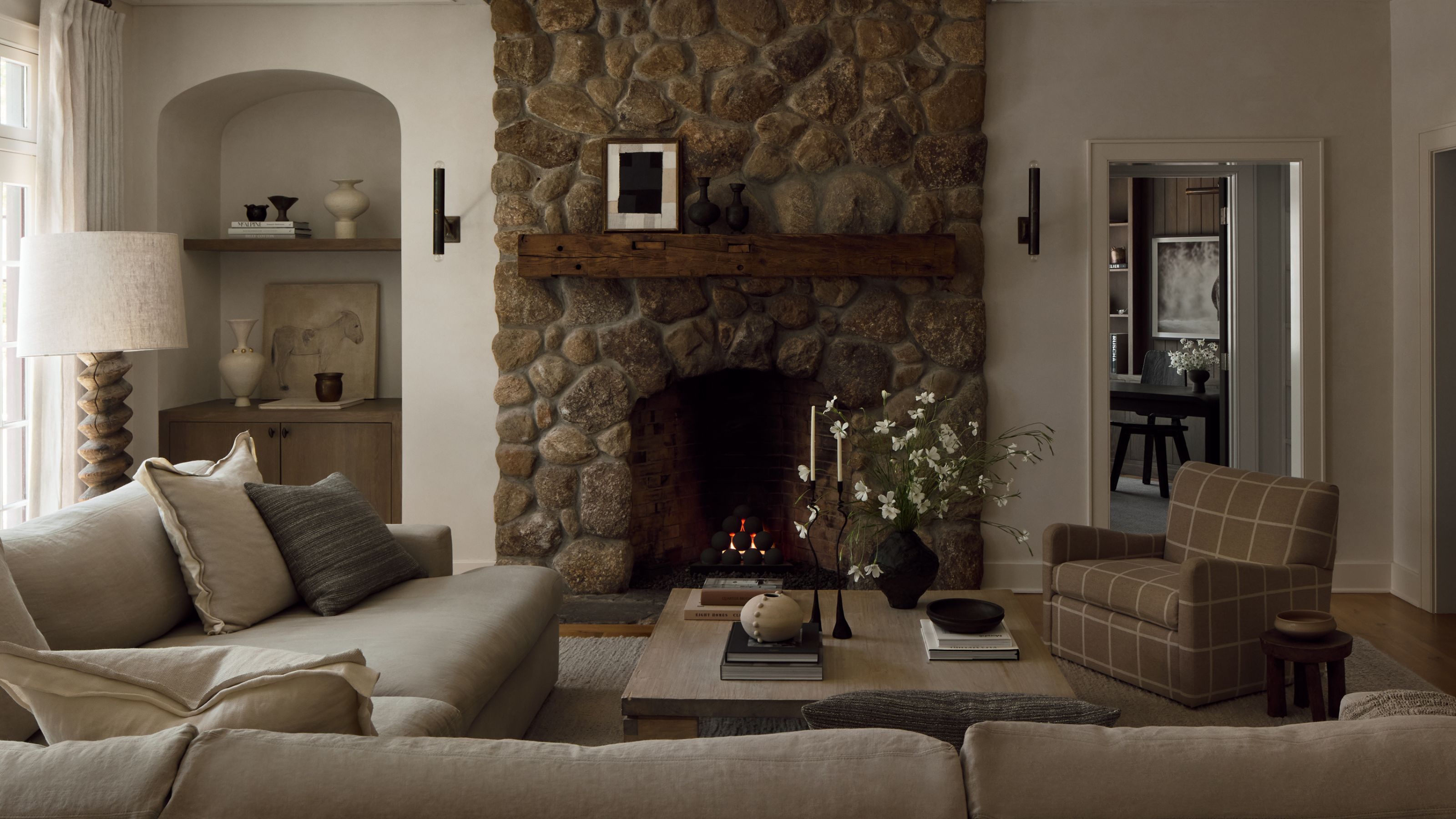 Neutral living room with a large stone fireplace and an arched alcove