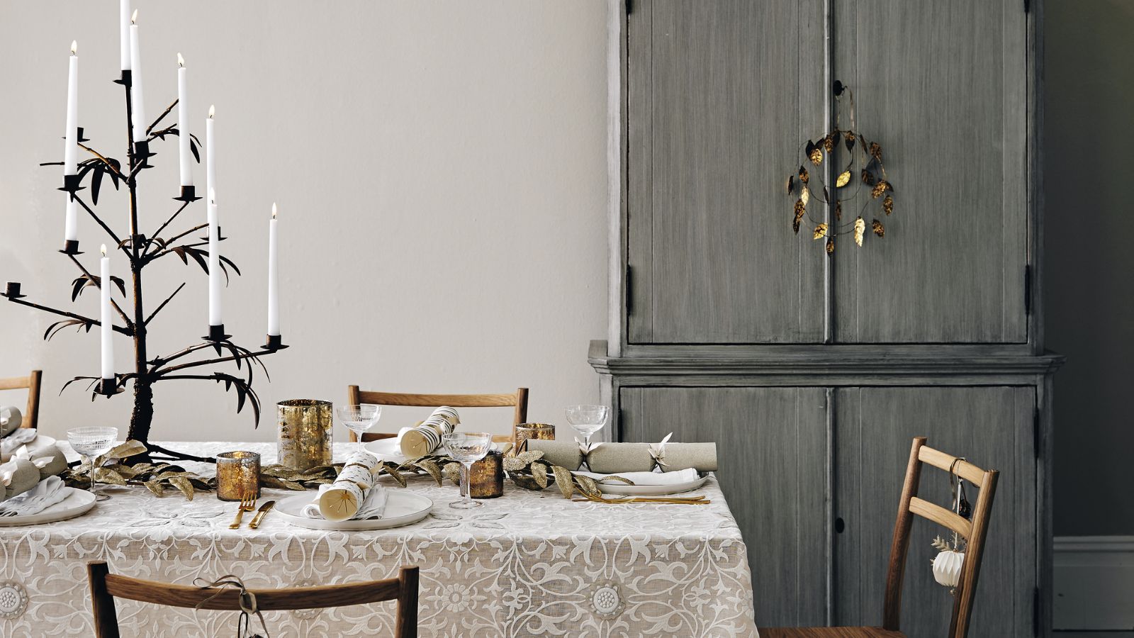 Christmas table with taupe floral tablecloth, rustic wood chairs, and white dinnerware